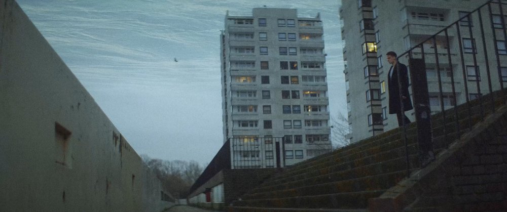 Guy arrives to the stairs while high-rises are in the background