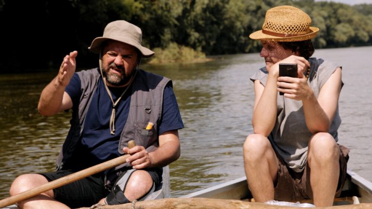 2 men is talking while on small boats on the river Tisza