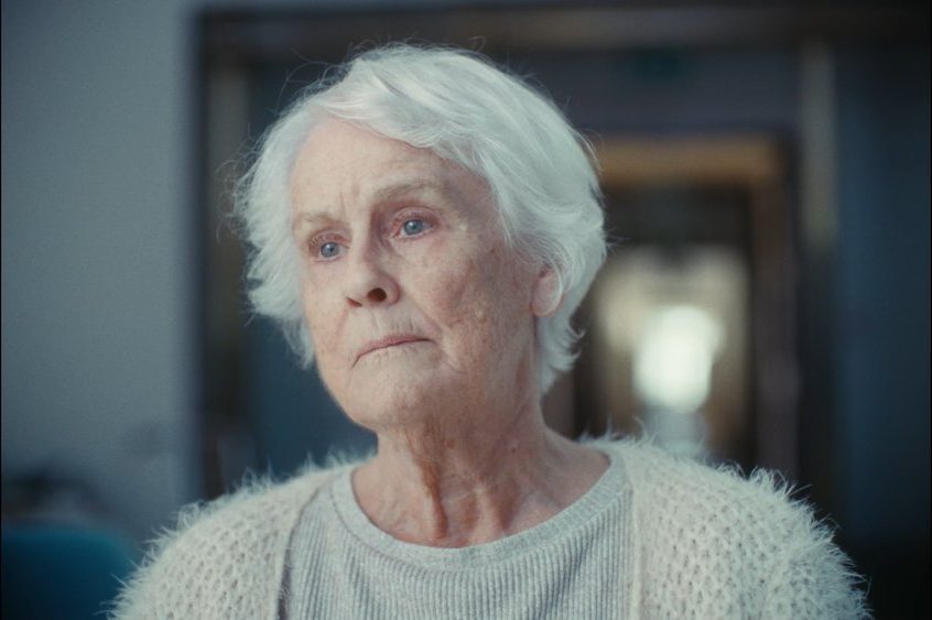Elderly woman looks out the window