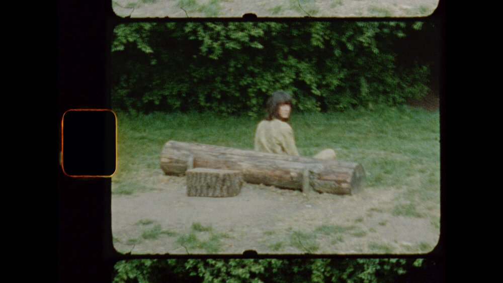 Woman looks back from behind a log