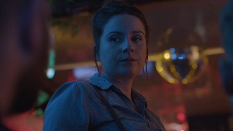 Woman looks down/left to a guy in a dive bar
