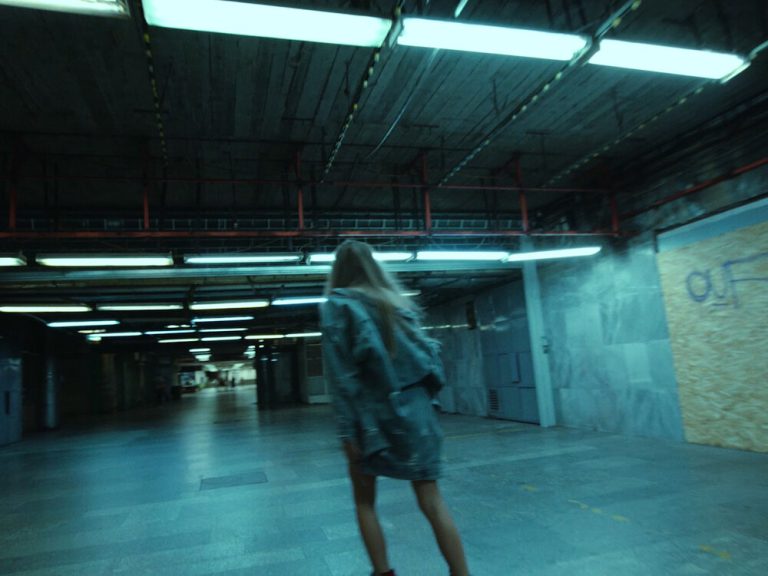 Woman is rollerskating away in a fluorescent light lit underground stop
