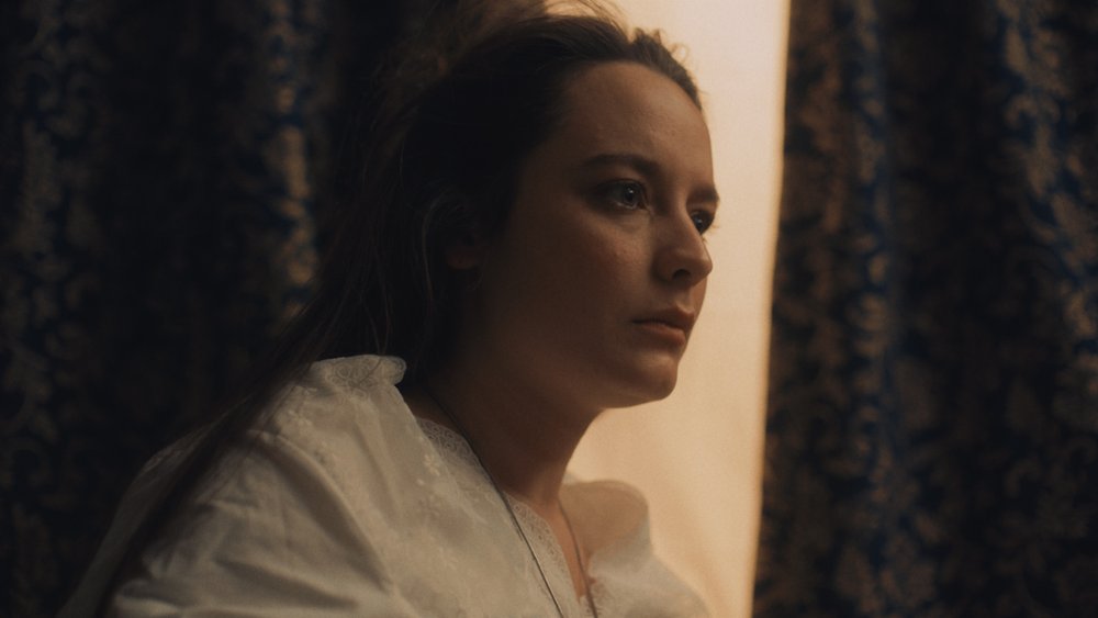 Woman sits up in bed and looks camera right
