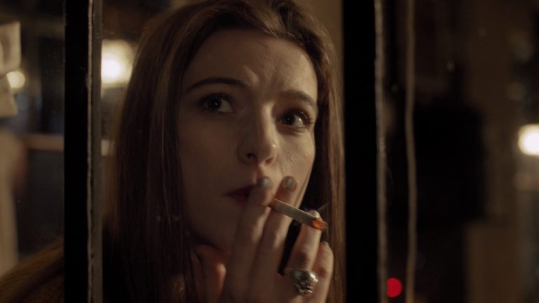 Woman looking out the window in a pub while smoking.