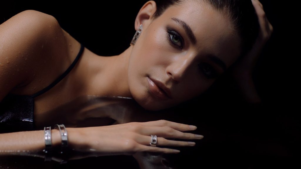 Model looks in the camera while laying in water. High contrast.